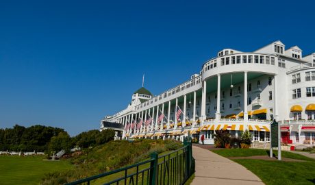 1. Mackinac Island: Timeless Victorian Elegance Why Mackinac Island Tops Our List Mackinac Island offers old Victorian charm where life runs at a slower pace, making it the perfect antidote to modern life's hustle and bustle. This car-free island, accessible only by ferry, provides a unique stepping-back-in-time experience that's particularly magical during August's perfect weather. What Makes August Special on Mackinac Island August on Mackinac Island offers the best of both worlds: perfect weather for outdoor activities and the tail end of the busy summer season. The island's famous horse-drawn carriages clip-clop along tree-lined streets, while Victorian gardens reach their peak bloom. The Grand Hotel's legendary front porch provides stunning views of the Straits of Mackinac, where the waters of Lake Huron and Lake Michigan meet. Must-Do Activities Historic Exploration: Fort Mackinac offers fascinating glimpses into the island's military history, with live demonstrations and breathtaking views of the straits. The fort's cannon firings are particularly spectacular against August's clear blue skies. Culinary Delights: No visit to Mackinac Island is complete without experiencing the world-famous Mackinac Island fudge. Watch skilled fudge makers create this sweet treat through storefront windows, and sample the dozens of flavors available throughout the island. Outdoor Adventures: August weather is perfect for the island's 70+ miles of trails, whether you prefer hiking, biking, or horseback riding. The island's perimeter road offers an easy 8.2-mile bike ride with stunning lake views throughout. Luxury Accommodations: The Grand Hotel provides the ultimate in Victorian luxury, while the Island House Hotel offers special Labor Day packages for late August visitors. For budget-conscious travelers, several charming bed and breakfasts provide authentic island hospitality. Getting There and Around Ferry services from Mackinaw City and St. Ignace run frequently during August, with the journey itself being part of the experience. Once on the island, walking, biking, and horse-drawn carriages are your transportation options – no cars allowed! Recommended Links: Mackinac Island Tourism Bureau Grand Hotel Mackinac Island Mackinac Island State Park