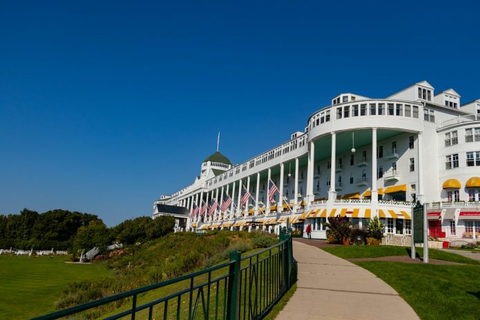 1. Mackinac Island: Timeless Victorian Elegance Why Mackinac Island Tops Our List Mackinac Island offers old Victorian charm where life runs at a slower pace, making it the perfect antidote to modern life's hustle and bustle. This car-free island, accessible only by ferry, provides a unique stepping-back-in-time experience that's particularly magical during August's perfect weather. What Makes August Special on Mackinac Island August on Mackinac Island offers the best of both worlds: perfect weather for outdoor activities and the tail end of the busy summer season. The island's famous horse-drawn carriages clip-clop along tree-lined streets, while Victorian gardens reach their peak bloom. The Grand Hotel's legendary front porch provides stunning views of the Straits of Mackinac, where the waters of Lake Huron and Lake Michigan meet. Must-Do Activities Historic Exploration: Fort Mackinac offers fascinating glimpses into the island's military history, with live demonstrations and breathtaking views of the straits. The fort's cannon firings are particularly spectacular against August's clear blue skies. Culinary Delights: No visit to Mackinac Island is complete without experiencing the world-famous Mackinac Island fudge. Watch skilled fudge makers create this sweet treat through storefront windows, and sample the dozens of flavors available throughout the island. Outdoor Adventures: August weather is perfect for the island's 70+ miles of trails, whether you prefer hiking, biking, or horseback riding. The island's perimeter road offers an easy 8.2-mile bike ride with stunning lake views throughout. Luxury Accommodations: The Grand Hotel provides the ultimate in Victorian luxury, while the Island House Hotel offers special Labor Day packages for late August visitors. For budget-conscious travelers, several charming bed and breakfasts provide authentic island hospitality. Getting There and Around Ferry services from Mackinaw City and St. Ignace run frequently during August, with the journey itself being part of the experience. Once on the island, walking, biking, and horse-drawn carriages are your transportation options – no cars allowed! Recommended Links: Mackinac Island Tourism Bureau Grand Hotel Mackinac Island Mackinac Island State Park