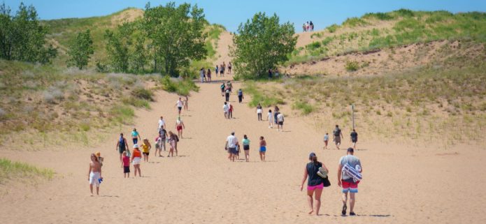 The Sleeping Bear Dunes height is one of those facts that sounds made up until you are standing at the base looking up and wondering what life decisions brought you to this moment. These dunes rise up to 450 feet above Lake Michigan — that is taller than a 40-story building — making them among the highest freshwater coastal dunes on the planet. I have stood at the top with wind whipping sand into my face and watched grown adults sit down mid-descent and refuse to move. I have also watched kids sprint up like mountain goats while their parents quietly reconsidered their fitness levels. Whether you are here for the views, the geology, or simply to prove something to yourself, understanding the scale of what you are looking at changes everything about the experience. Located inside Sleeping Bear Dunes National Lakeshore on the northwestern coast of Michigan's Lower Peninsula, these ancient glacial giants are unlike anything else in the Midwest.